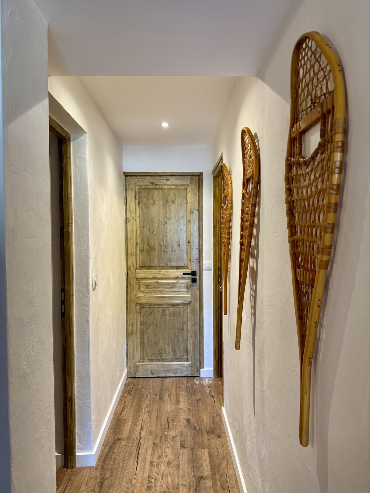 Couloir de l'appartement avec raquettes anciennes aux murs
