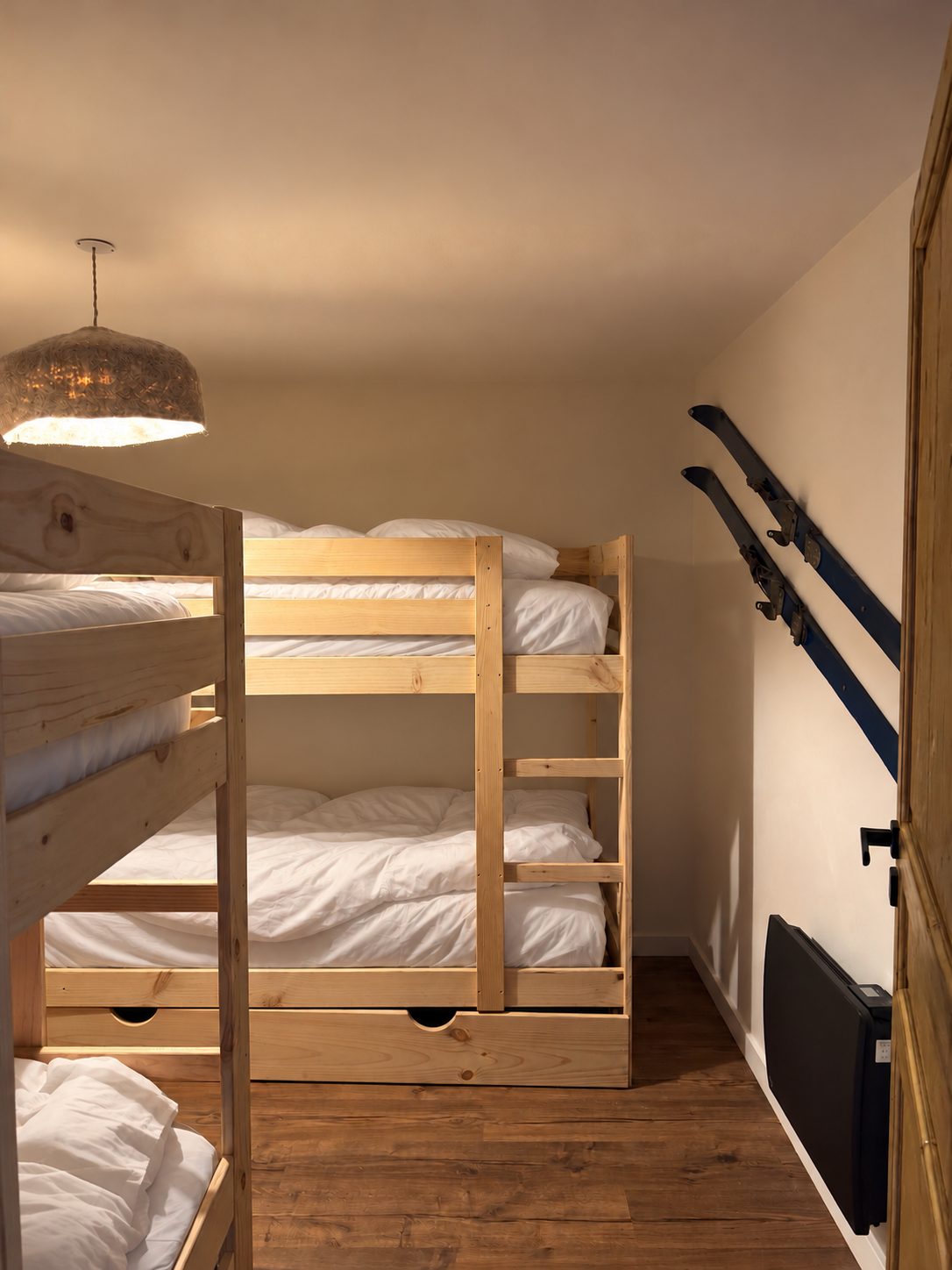 Dortoir de l'appartement, deux lits superposés en bois et skis anciens au mur