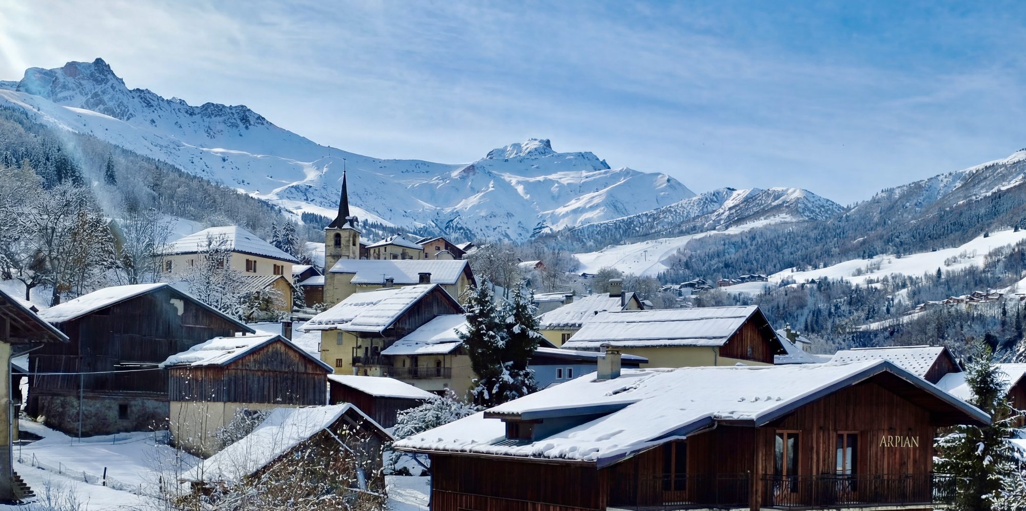 Le village des Avanchers sous la neige — clocher, sommets et le pignon du chalet Arpian