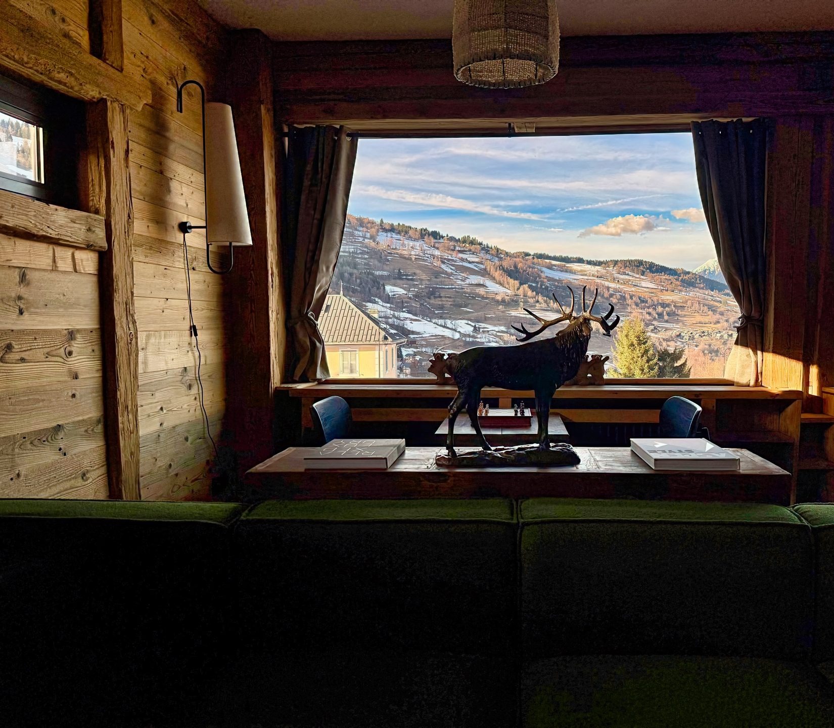 Vue signature du chalet — cerf en bronze, baie vitrée