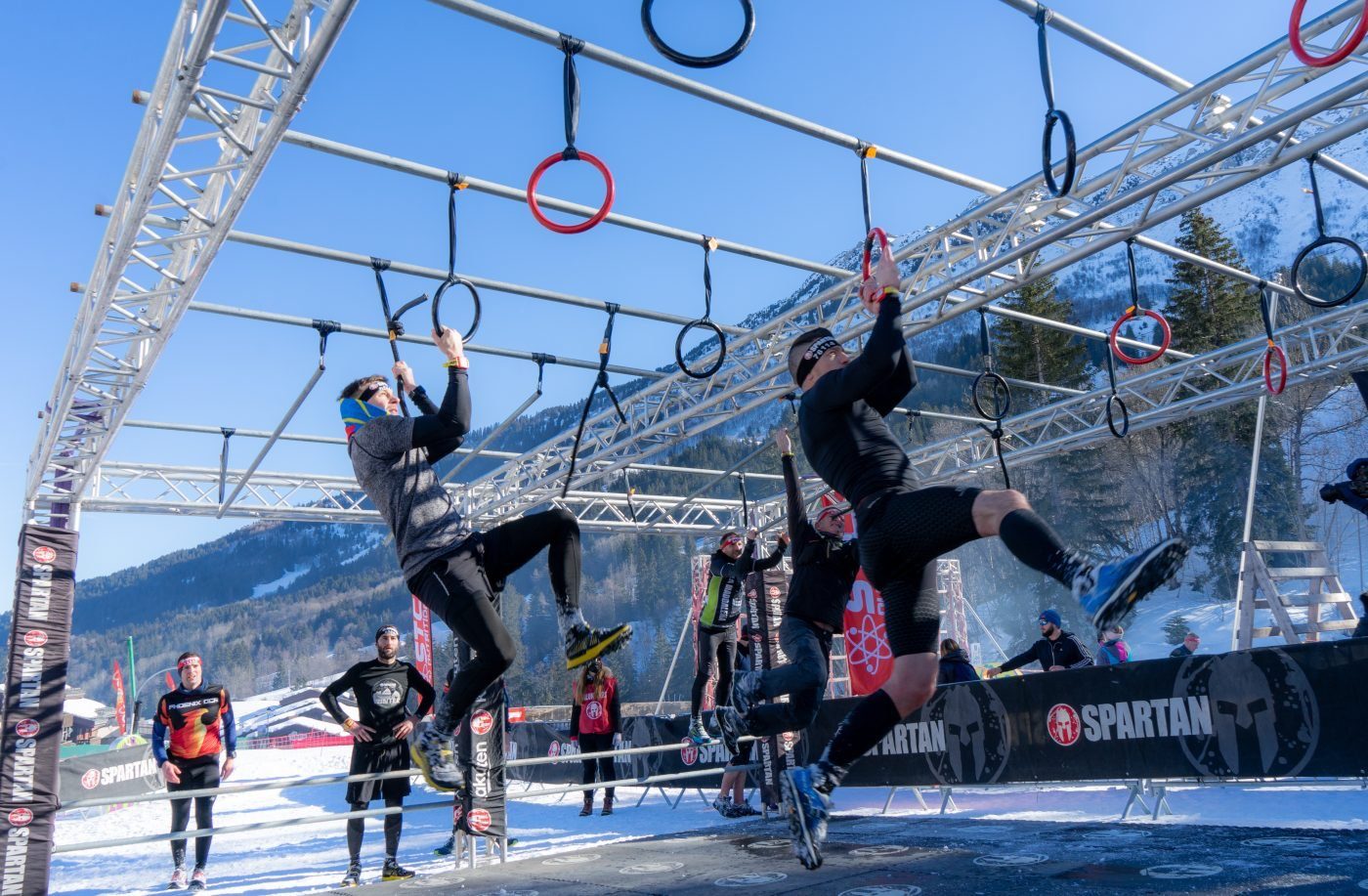 Participants à la Winter Spartan Race de Valmorel franchissant les anneaux sur la neige