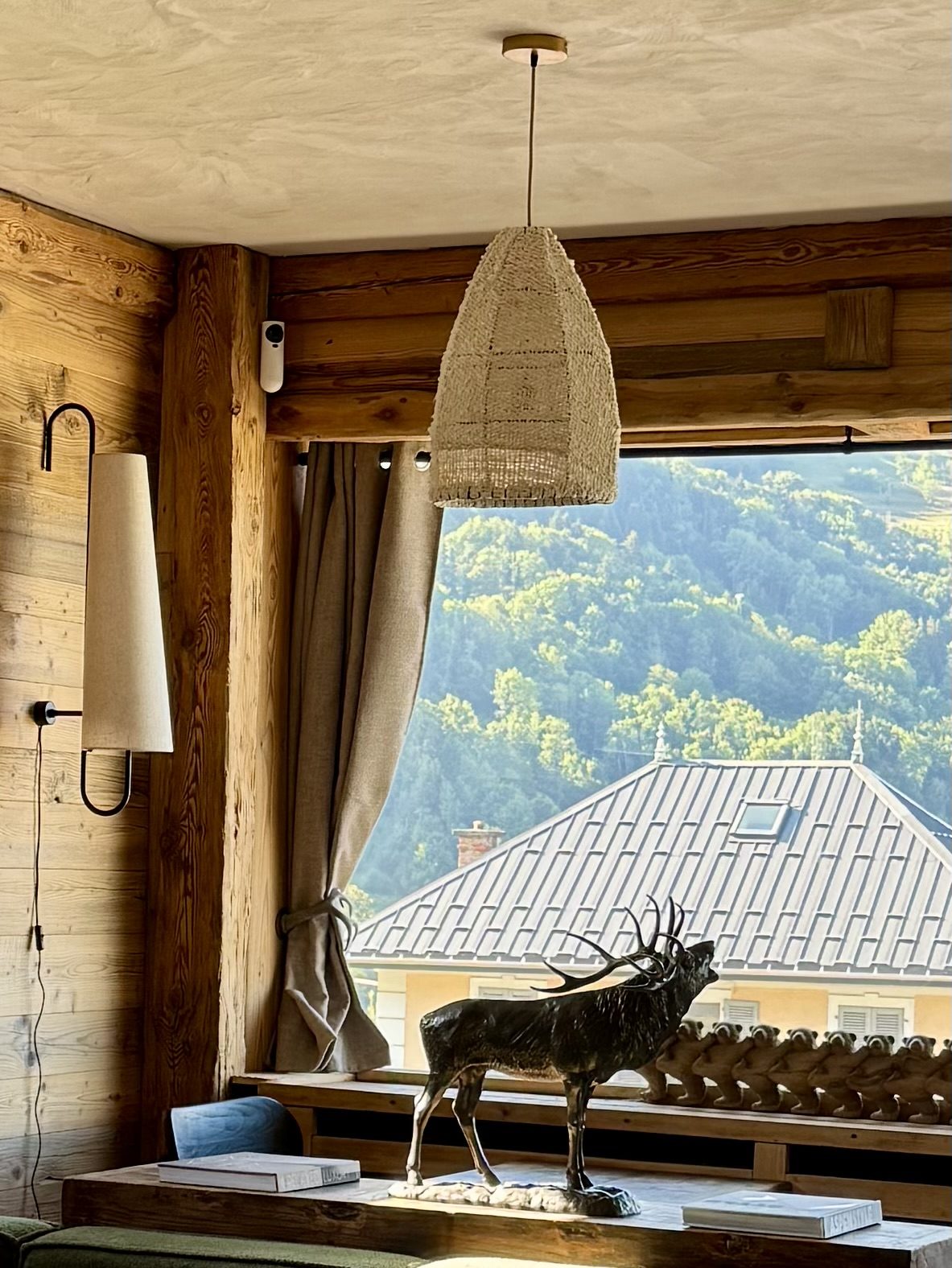Suspension en fibres naturelles et cerf en bronze devant la fenêtre