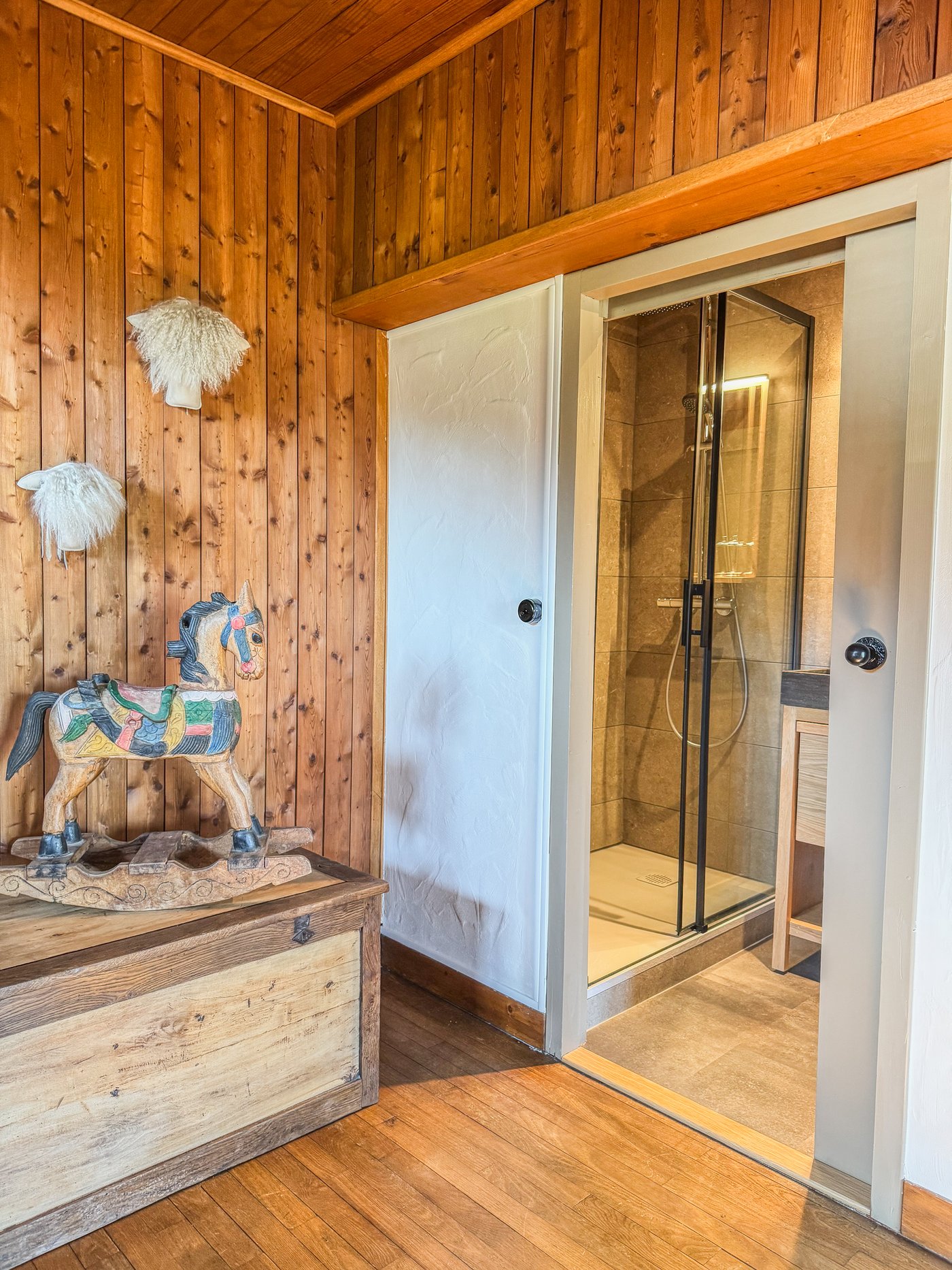 Détail chambre avec cheval-jouet en bois et accès douche