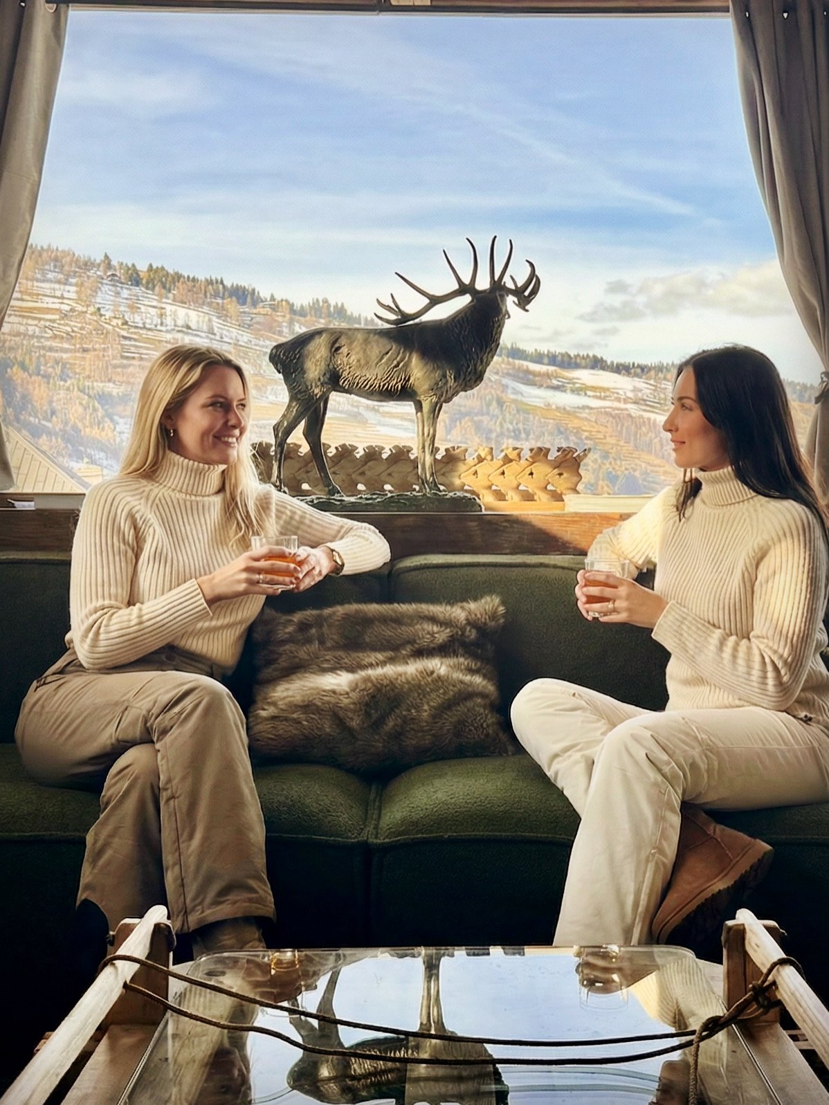 Deux amies sur le canapé vert avec cerf en bronze et vue