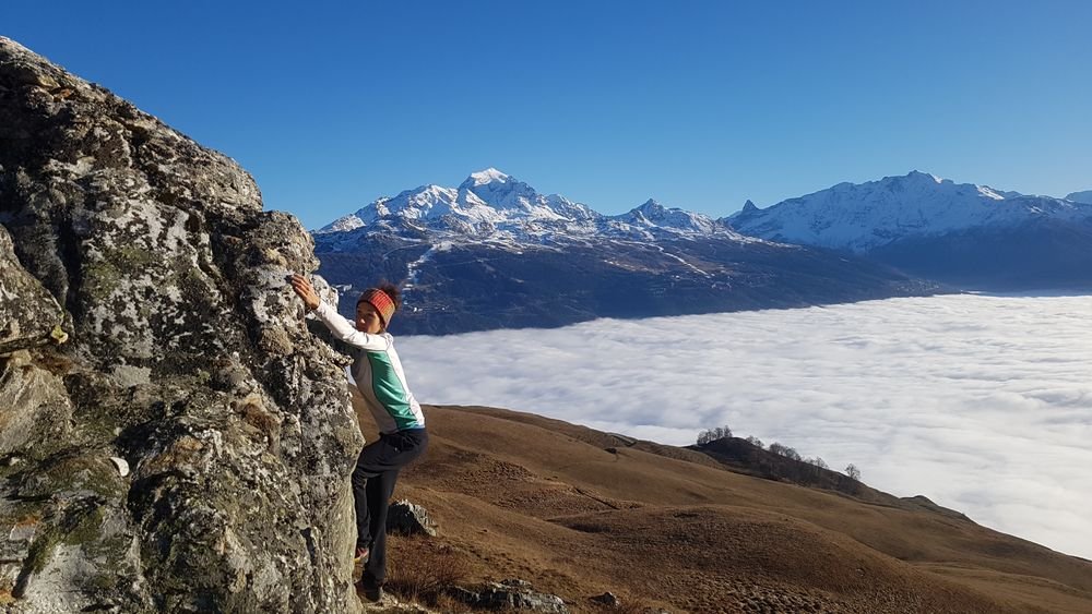 Grimpeur en bouldering sur rocher de Tarentaise, vue sur Mont-Blanc et mer de nuages