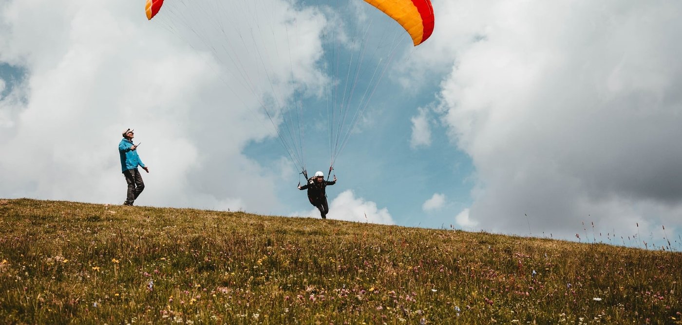 Décollage en parapente sur l'alpage de Valmorel, voile orange et jaune