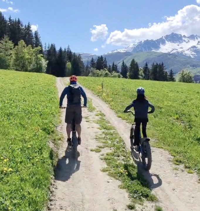 Adulte et enfant en trottinette électrique tout-terrain Valmo'Trott sur sentier d'alpage