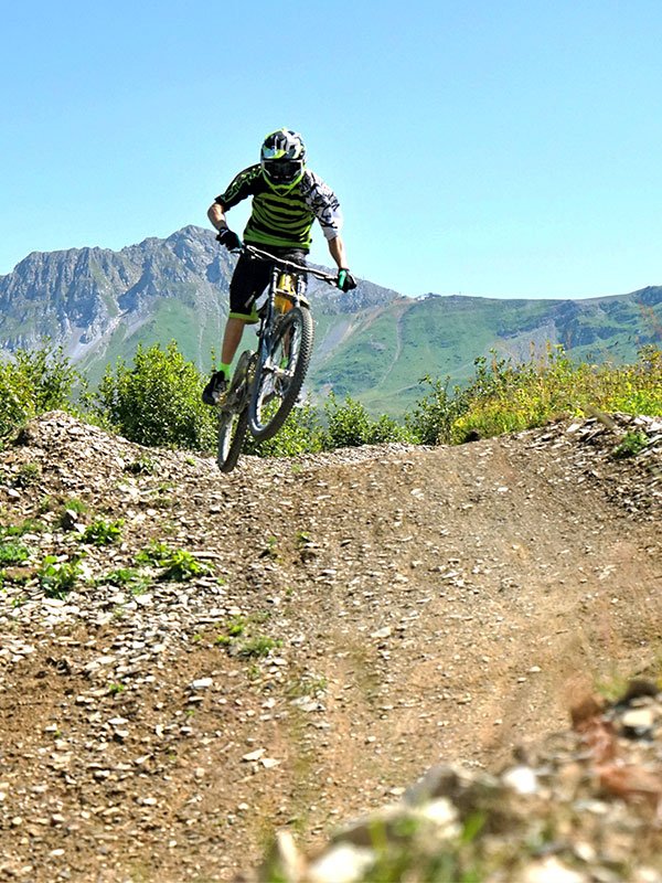 VTTiste sur piste de descente du bike park de Valmorel, sommets en arrière-plan
