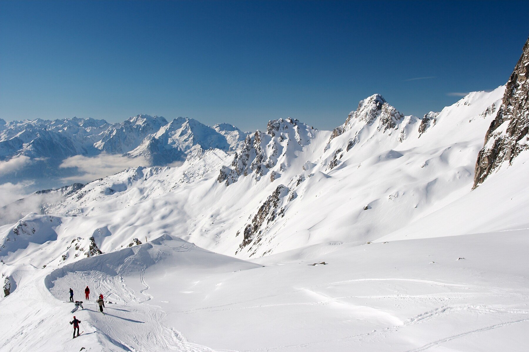 Skieurs en hors-piste sur les sommets enneigés du Grand Domaine — vue infinie sur les Alpes